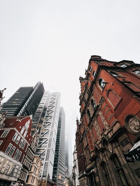 A busy urban street scene on Leman Street in Aldgate, showing pedestrians crossing the road and walking along the pavement, with a tall brick building decorated with colorful graffiti art on the left